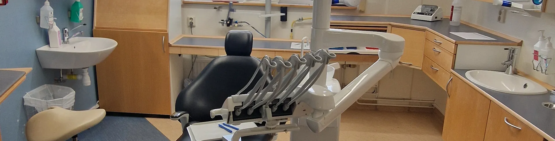 En tandläkarmottagning med en stol och ett handfat.